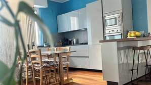 Une cuisine moderne avec des meubles blancs, un îlot central doté de tabourets et un four encastré.