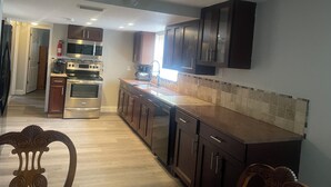 Una cocina con electrodomésticos de acero inoxidable, armarios de madera y salpicadero de azulejos.
