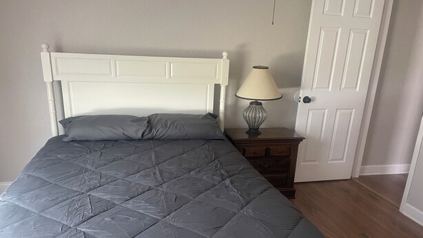 A bed with a quilt, a nightstand with a lamp, and a door.