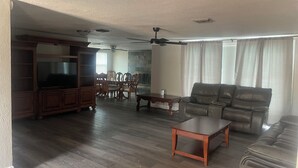 Amplia sala de estar con chimenea, sofá de cuero, mesa de comedor de madera y televisor.