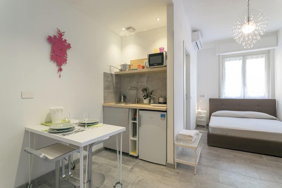 Quarto de hotel compacto com cozinha compacta, área de refeições e uma cama.