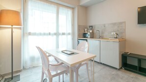 Une cuisine moderne avec un coin repas, comprenant une table et des chaises blanches, un four à micro-ondes et un évier.
