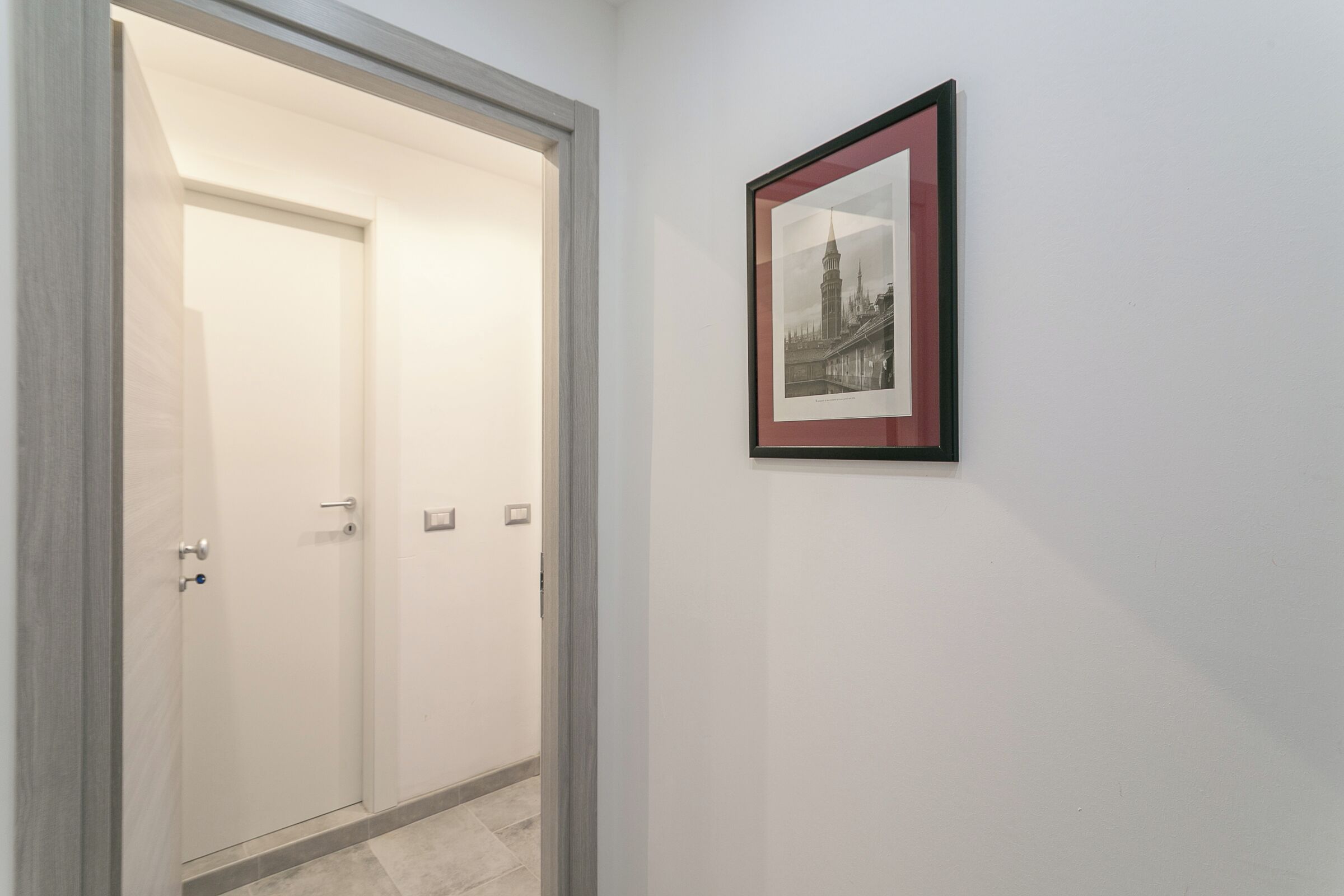 A hallway with a framed picture of a historic building on the wall.