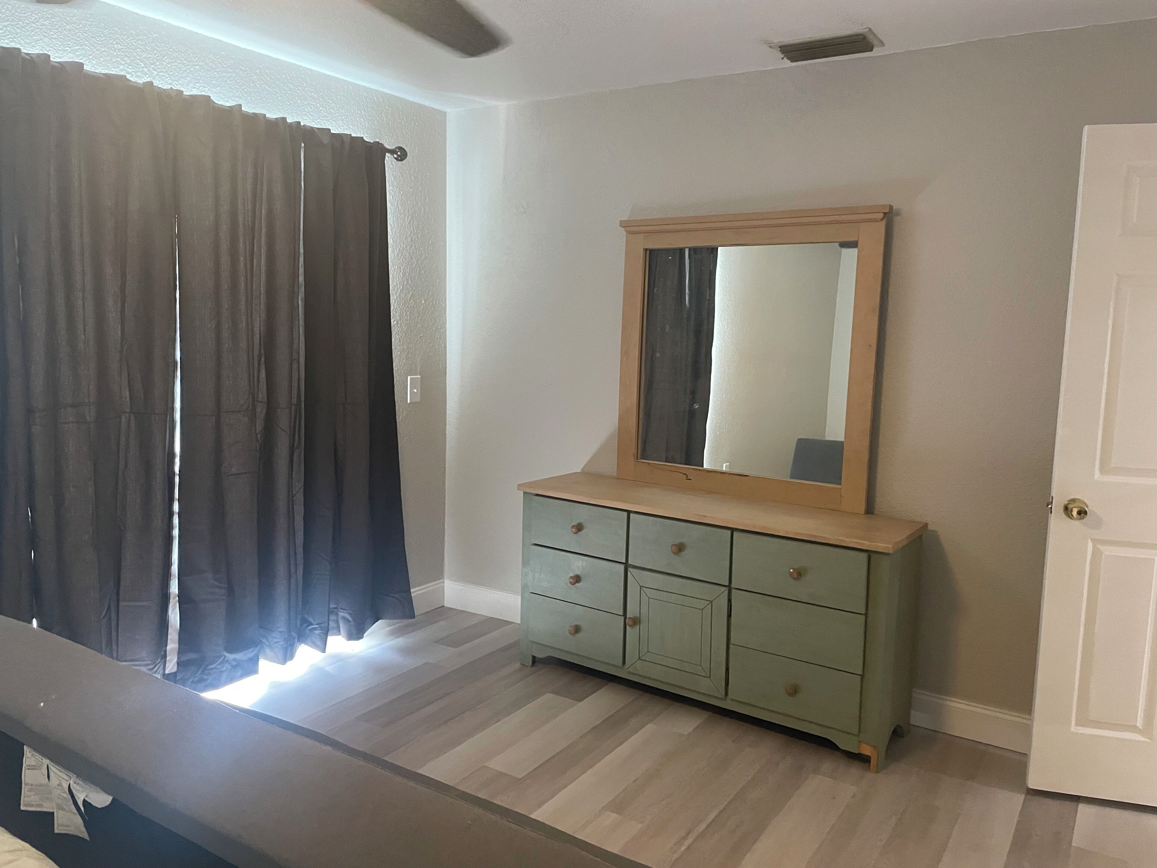 A room with a wooden dresser, a mirror, and a door.