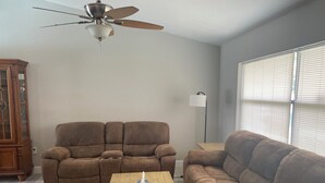 A living room with two brown sofas, a wooden coffee table, a ceiling fan, a floor lamp, and a window with blinds. - Terrific 3-bedroom house with bird caged swimming pool in Spring Hill (Spring Hill)
