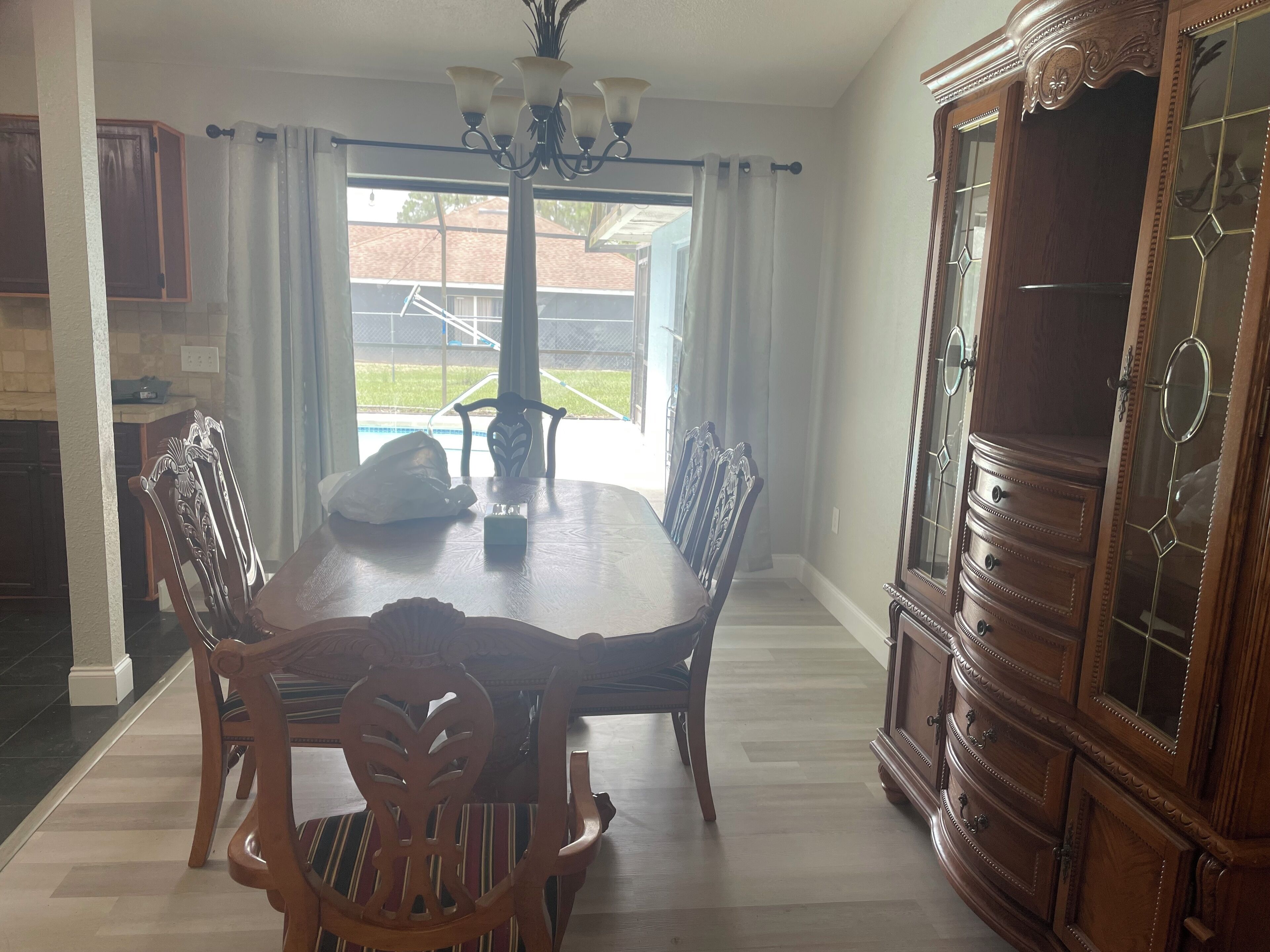 A dining room with a wooden table, chairs, and a cabinet.