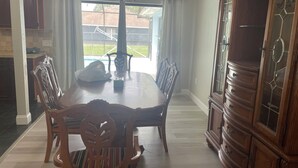 A dining room with a wooden table, chairs, and a cabinet. - Terrific 3-bedroom house with bird caged swimming pool in Spring Hill (Spring Hill)