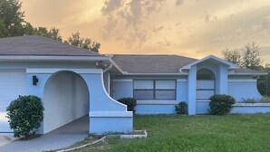 A residential house with a sloped roof, a front entrance with an archway, and a small front yard with grass and shrubs. - Terrific 3-bedroom house with bird caged swimming pool in Spring Hill (Spring Hill)