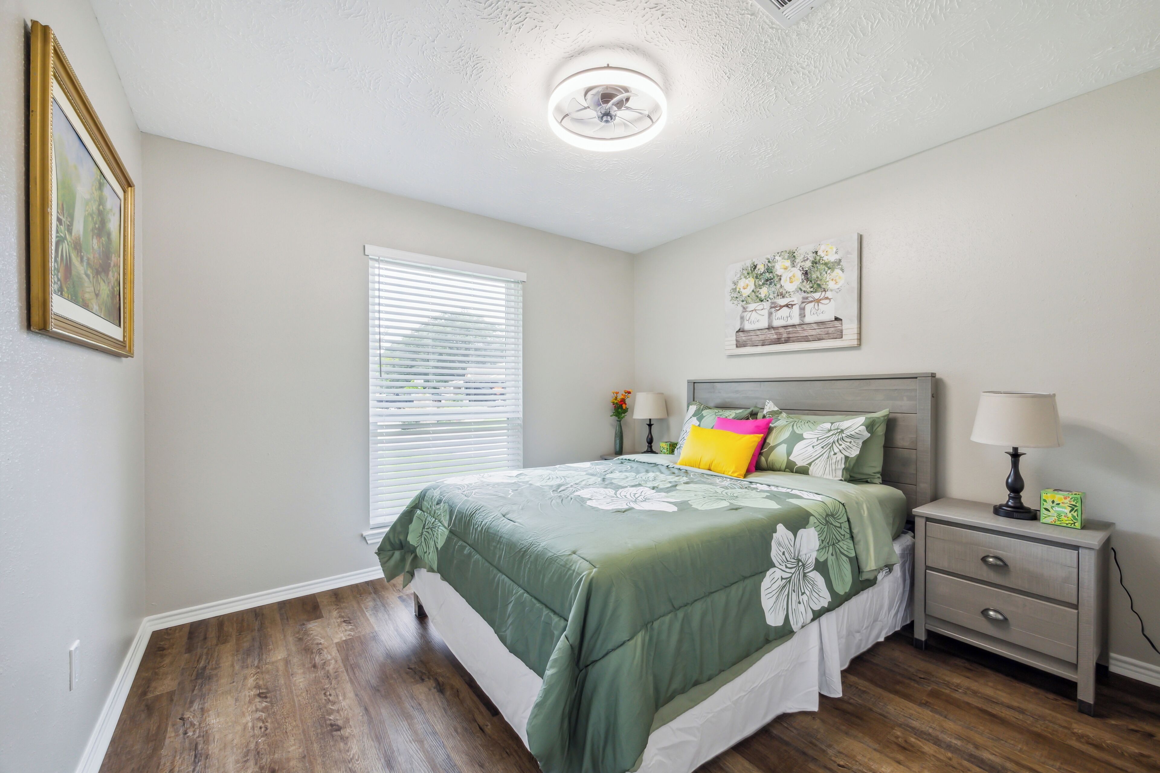A bedroom with a bed, nightstand, and a ceiling fan.