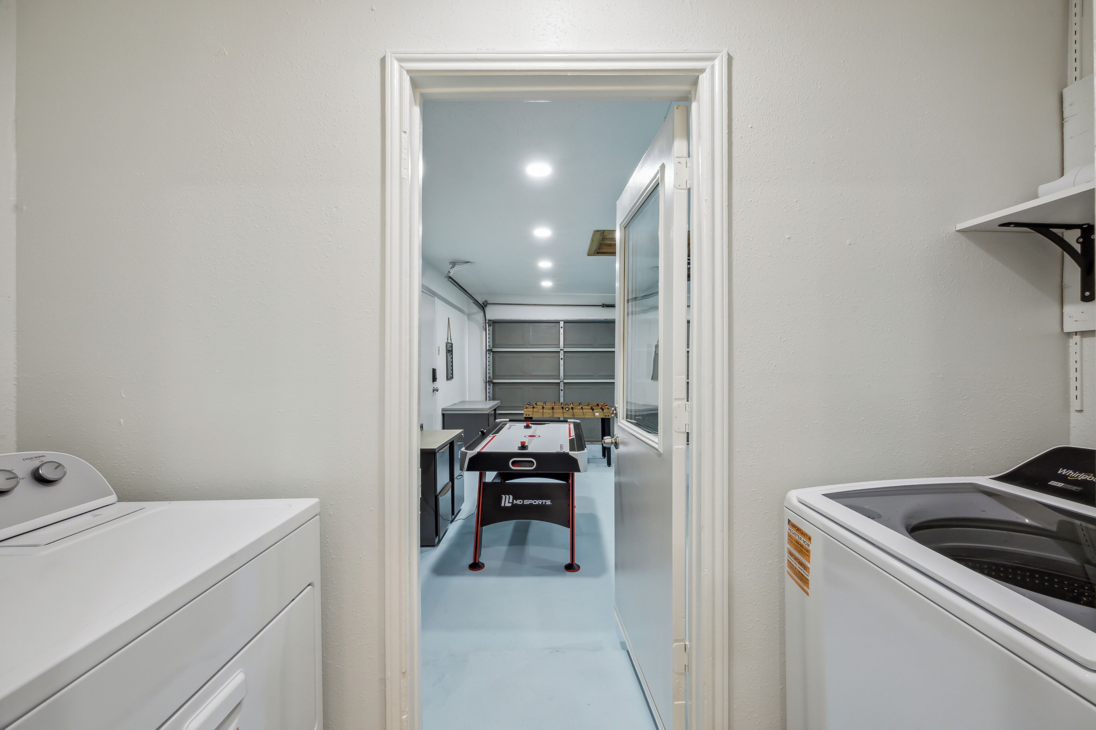 A laundry room with a washing machine, dryer, and ironing station.