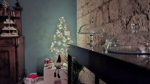 Una habitación acogedora con un armario de madera, un árbol de Navidad y una vitrina de vidrio.