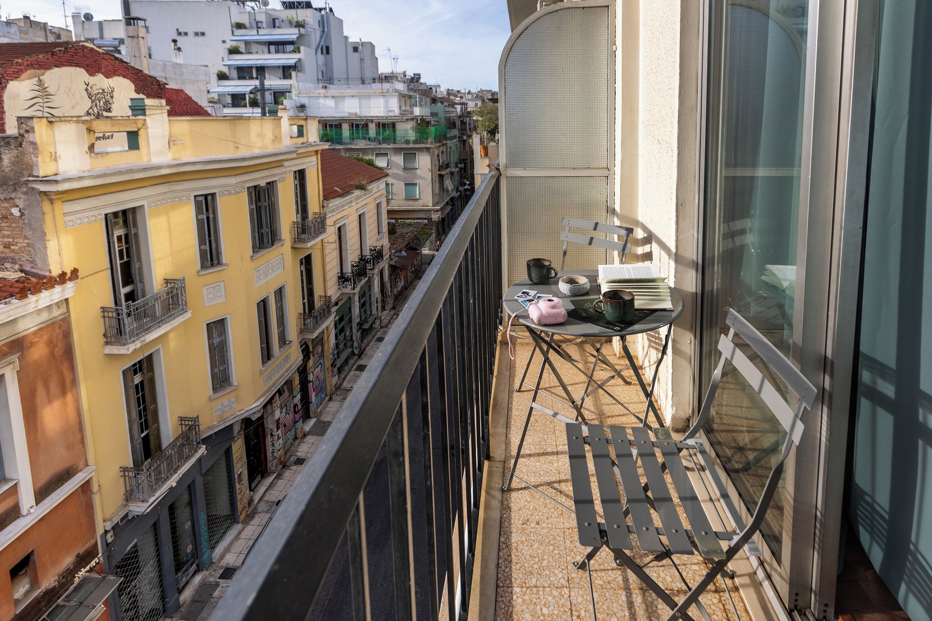 A balcony with a table, chairs, and a view of a city street.