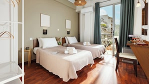 Ein Hotelzimmer mit zwei Betten, Holzboden, einem Balkon mit Blick und einem Schreibtisch mit Stuhl.