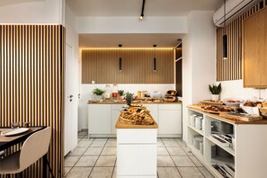Une cuisine moderne dotée d’un îlot central, de meubles blancs et d’un mur décoré de lambris en bois.