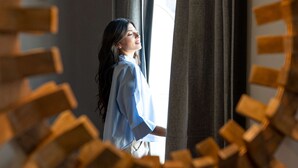 Ein Zimmer mit einer runden Holzkonstruktion im Vordergrund, eine Person steht am Fenster, und es gibt einen Blick nach draußen.