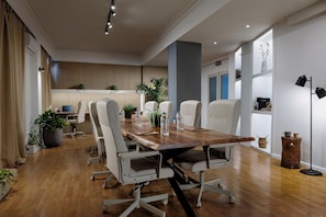 A modern conference room with a wooden table, white chairs, potted plants, and a whiteboard. - The Square Hotel by X&N (Athens)