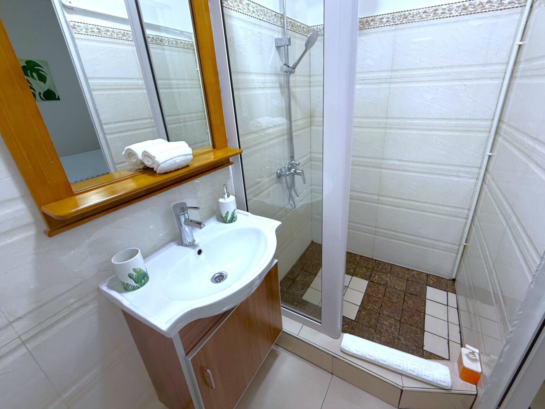 A bathroom with a sink, mirror, and shower.