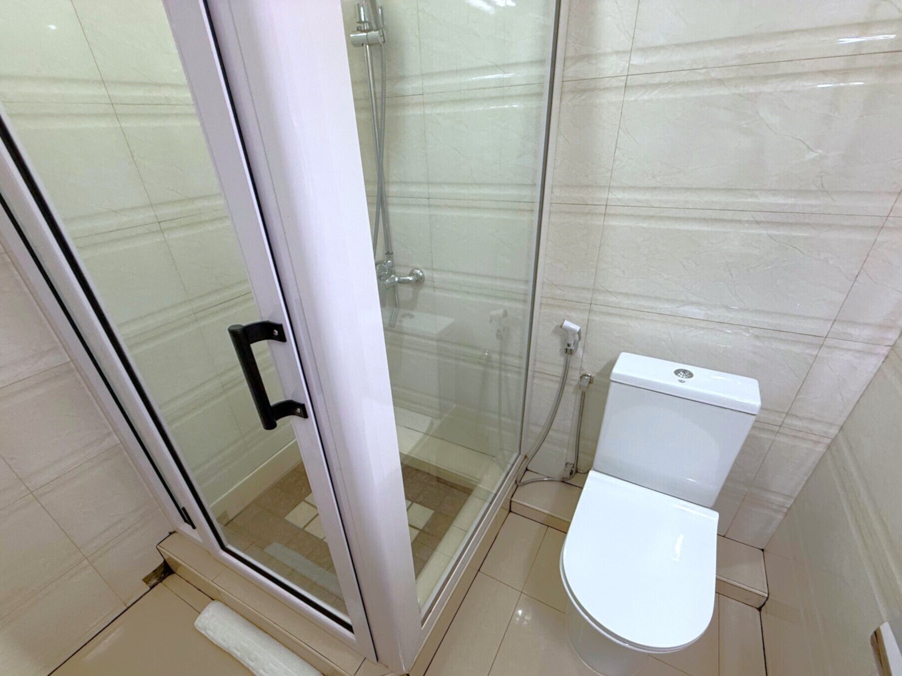 Un baño con ducha envuelta en vidrio, inodoro blanco y paredes con azulejos.