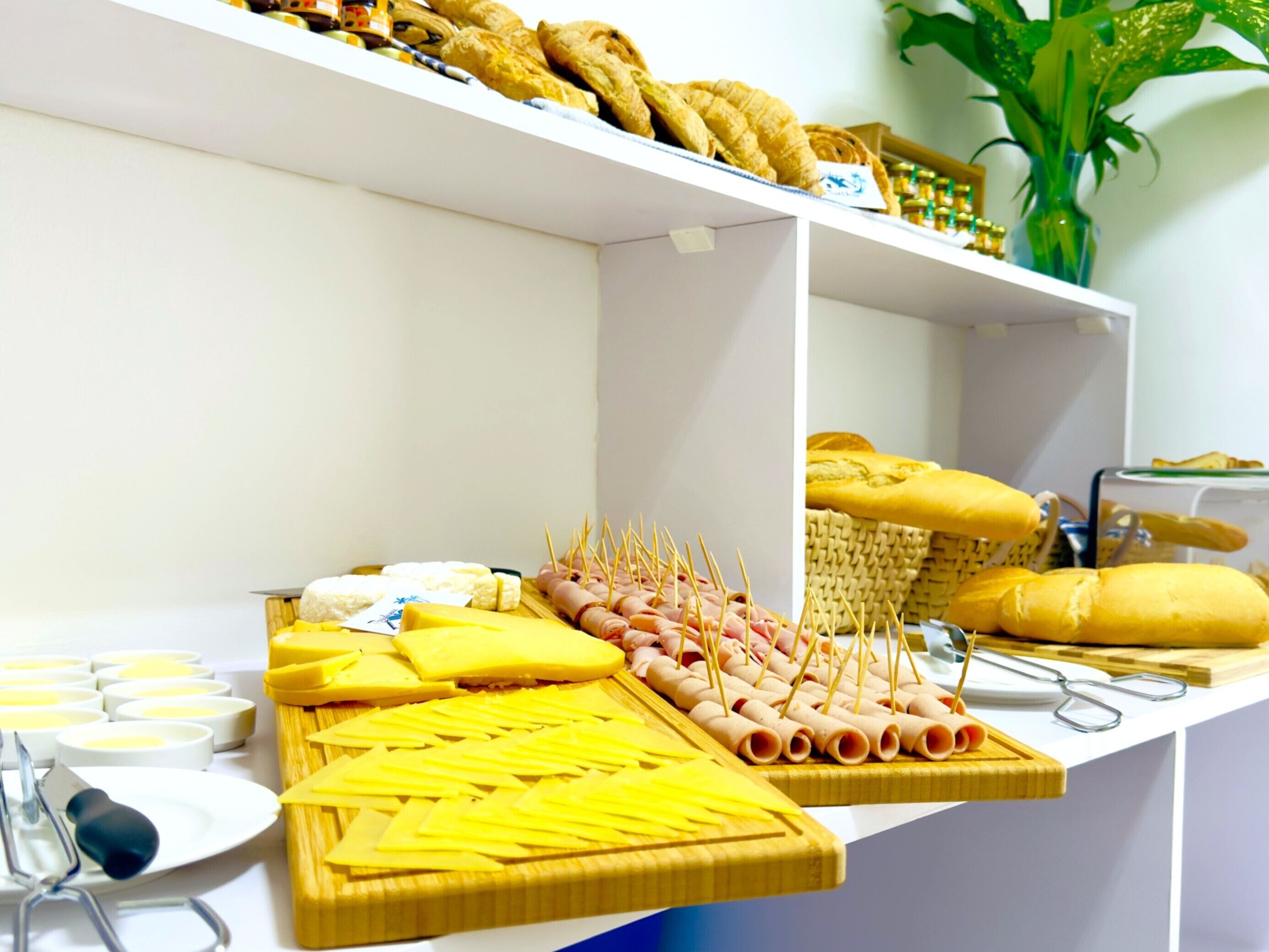 Un buffet con diversi cibi, tra cui formaggi, salumi e pane.