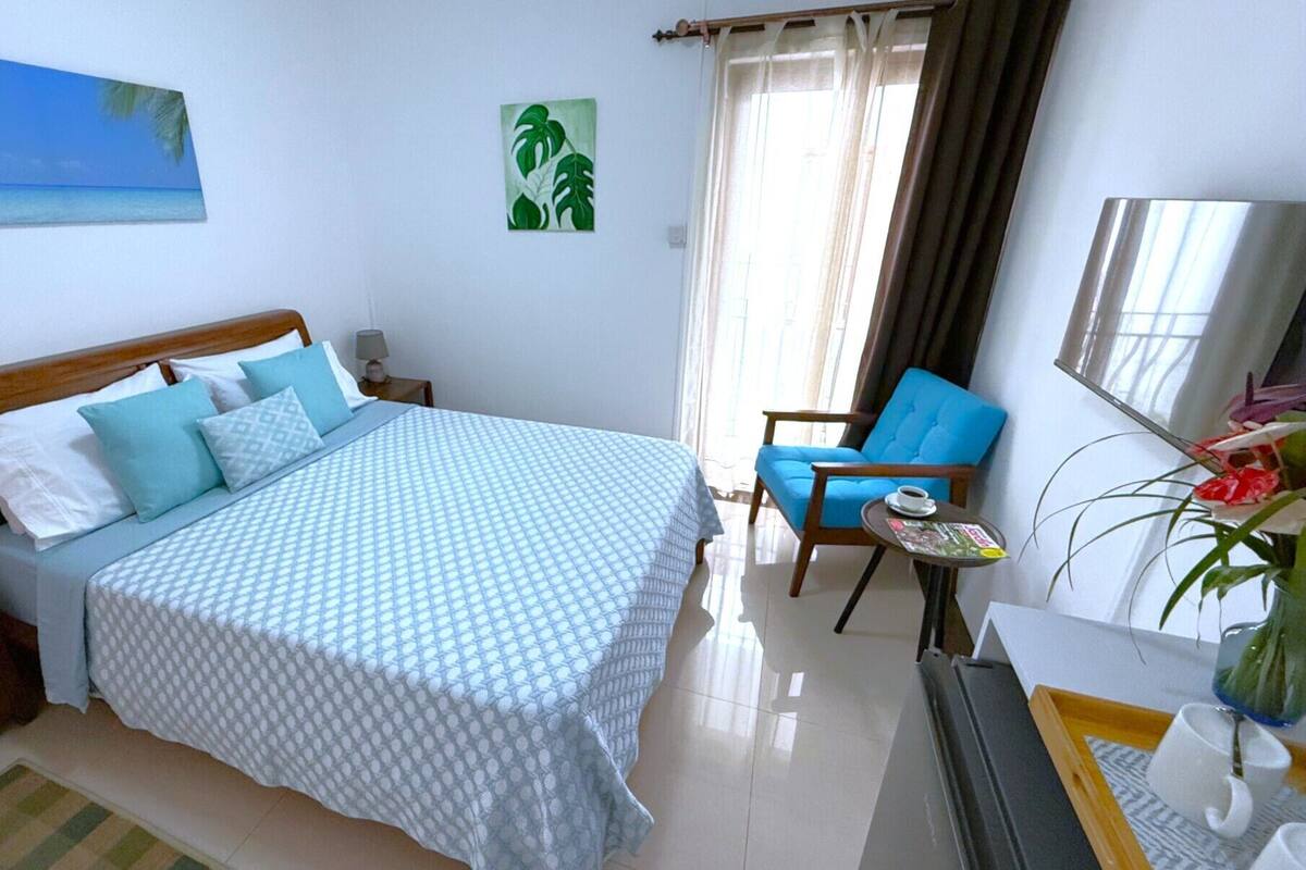 Une chambre d’hôtel avec un lit, une chaise, une petite table avec une tasse et un miroir.