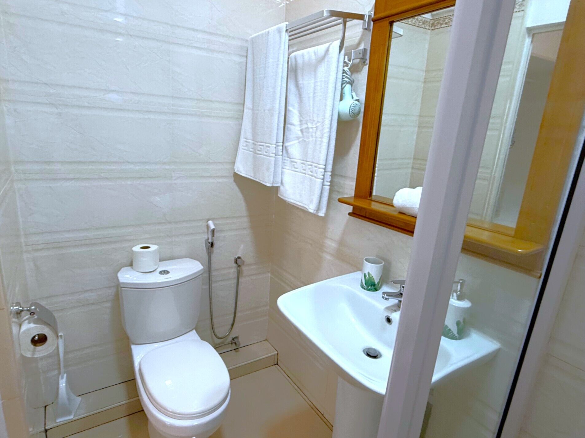 Ein kleines, sauberes Badezimmer mit Toilette, Bidet, Waschbecken und Spiegel.