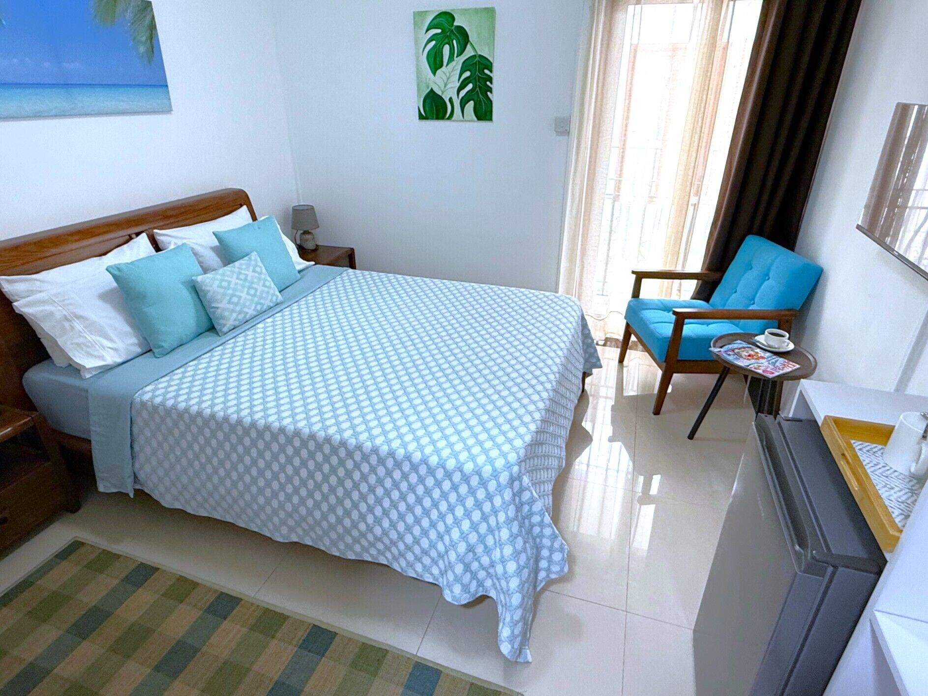 Una camera da letto con un letto, una sedia, un tavolo, una lampada e un quadro appeso al muro.