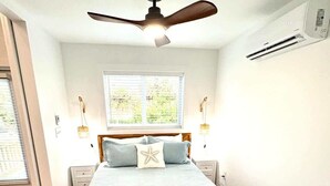 A bedroom with a bed, a ceiling fan, a window, and a nightstand. - 120 Falkirk Small Pet Friendly Cottage near Beach (Fort Myers Beach)