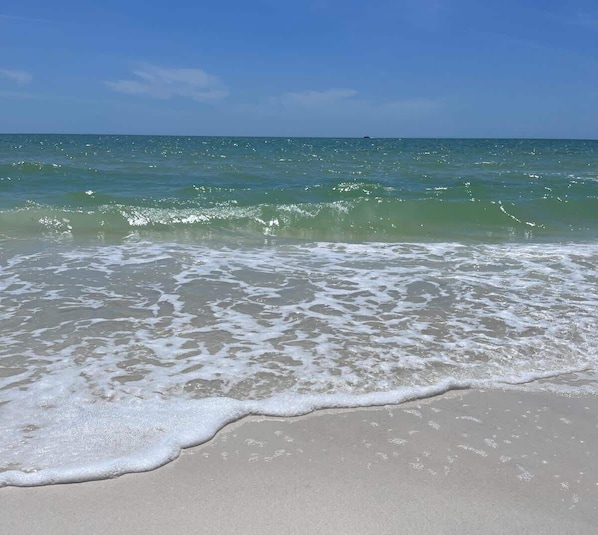 A beach with clear water and a sandy shore.
