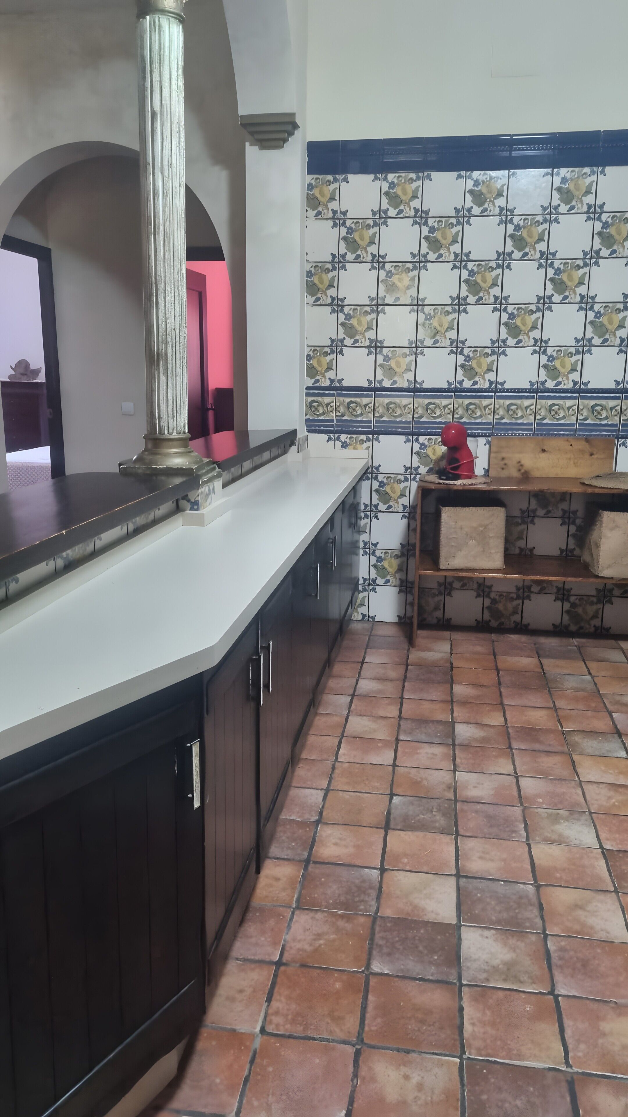 A kitchen with a central island, dark cabinets, a tiled backsplash, and a tiled floor.