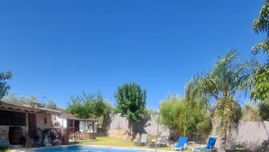 A backyard with a swimming pool, a large tree, and a patio area. - Country House 'Casa Rural Valle' with Mountain View, Private Pool and Air Conditioning (La puebla de los infantes)