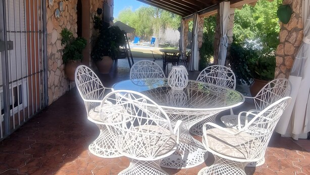 An outdoor patio with hexagonal tiled flooring, white wicker furniture, and a stone wall. - Country House 'Casa Rural Valle' with Mountain View, Private Pool and Air Conditioning (La puebla de los infantes)