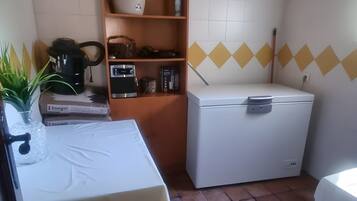 Una cocina con una mesa, estanterías, una lavadora y suelo de baldosas.