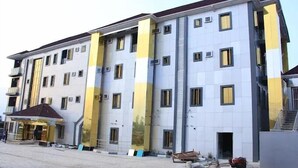Ein mehrstöckiges Gebäude mit modernem architektonischen Design, das mehrere Balkone und einen überdachten Eingangsbereich aufweist.