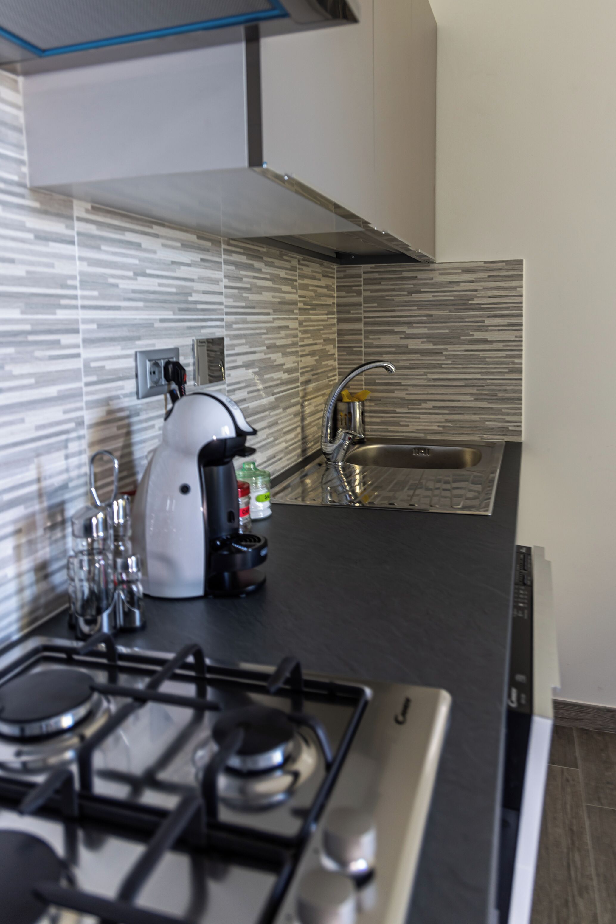 A modern kitchen with a gas stove, a coffee maker, and a sink.