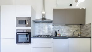 Μια σύγχρονη κουζίνα με εντοιχισμένες συσκευές, μια εστία αερίου και ένα φούρνο μικροκυμάτων από ανοξείδωτο ατσάλι.