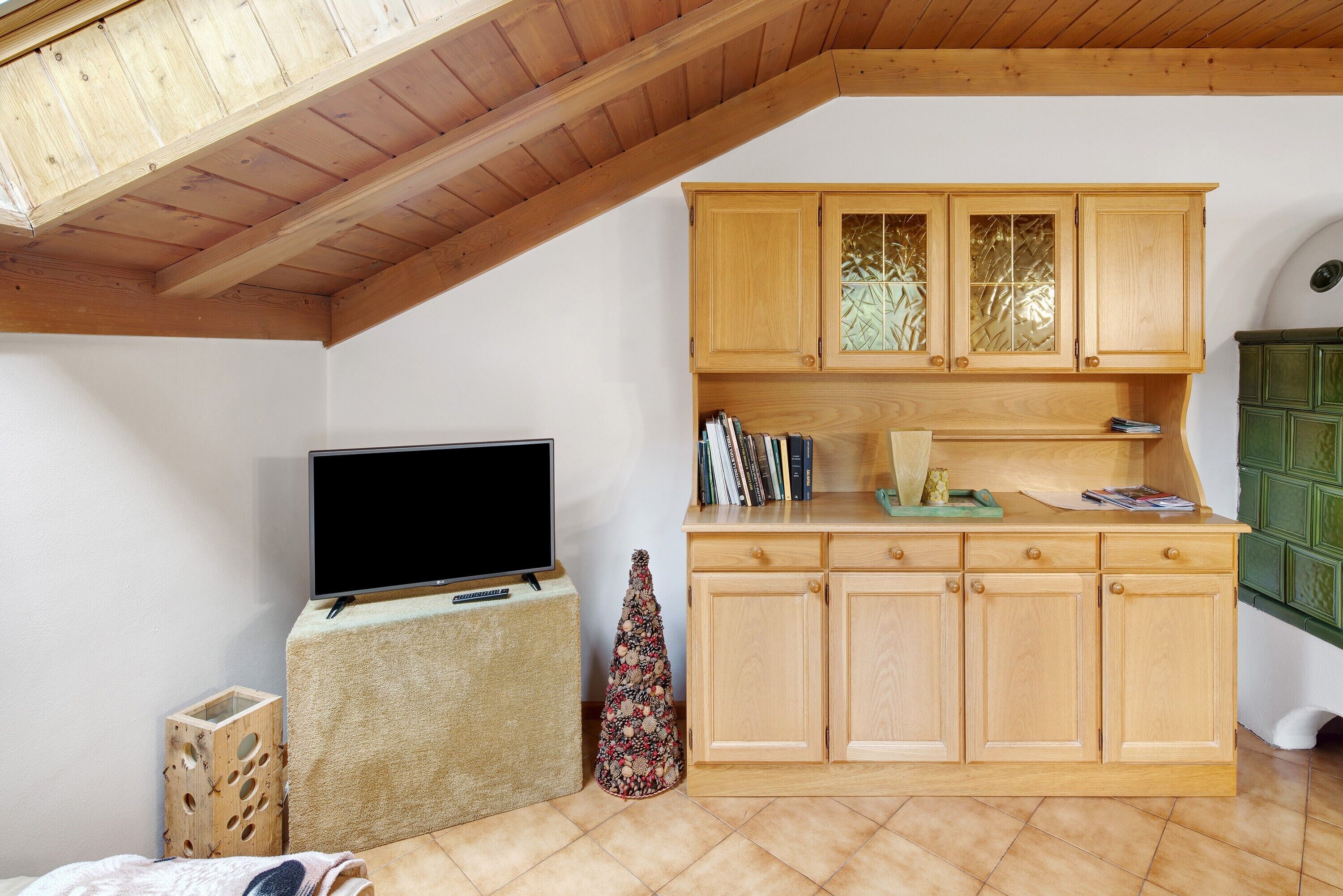 A kitchen with wooden cabinets, a television on a stand, and a small Christmas tree.