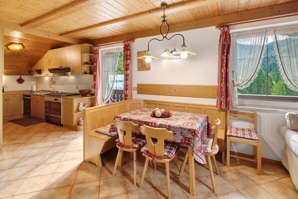Una cocina acogedora con armarios de madera, una mesa de comedor con sillas y una ventana con cortinas.