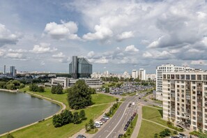 A cityscape with a large body of water, a road with parked cars, and modern buildings. - Stylish apartment with a river view (Minsk)
