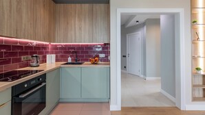 Una cocina moderna con armarios de madera, un protector contra salpicaduras rojo y un horno empotrado.