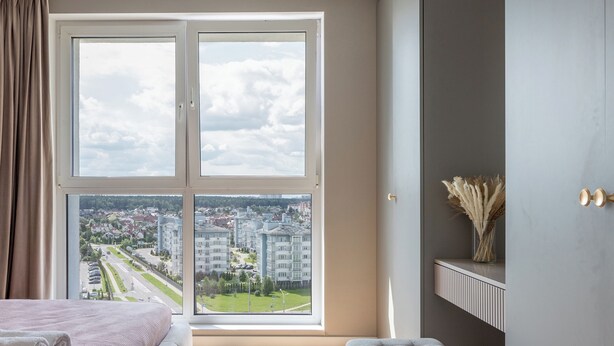 Un dormitorio moderno con un ventanal grande, una cama, un banco y un estante de pared con objetos decorativos.