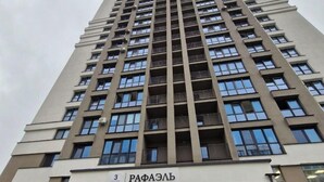 Un edificio alto y moderno con varios balcones y ventanas amplias.