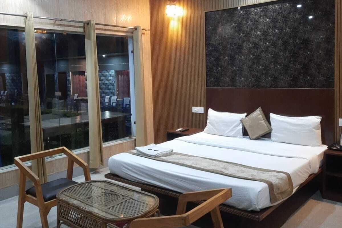 Hotellihuone, jossa on suuri sänky, kaksi yöpöytää, kattotuuletin ja näkymä lasiovesta.