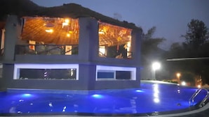 A building with a pool in front, featuring a modern design with a flat roof and large windows. - sky ganga resort (Rishikesh)