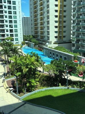 A residential building with a swimming pool surrounded by greenery and a paved walkway. - Serenity of your soul, blissful escape and dreamland staycation (Pasay City)