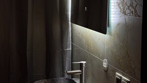 A modern bathroom with a marble sink, a large mirror, and a shower curtain.