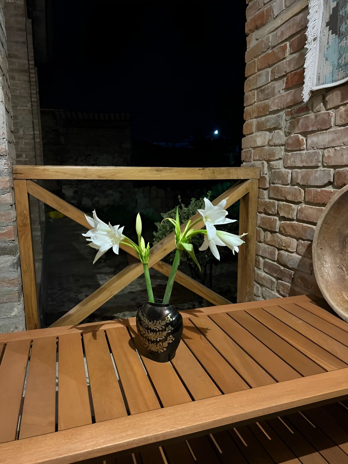 A wooden table with a black vase containing white flowers.