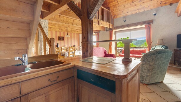 Interior de madeira com cozinha, área de refeições e vista para o exterior.