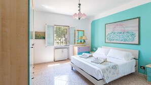 A bedroom with a bed, a nightstand, a dresser, a window, and a painting on the wall. - Villa Rita Ostuni with pool by Rentbeat  (Ostuni)