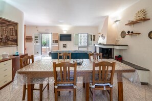 Un comedor con mesa y sillas, una cocina con estufa, y un área de estar con sofá.