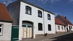 Ein weißes Gebäude mit rotem Ziegeldach, einer grünen Tür und einem Steinfundament.